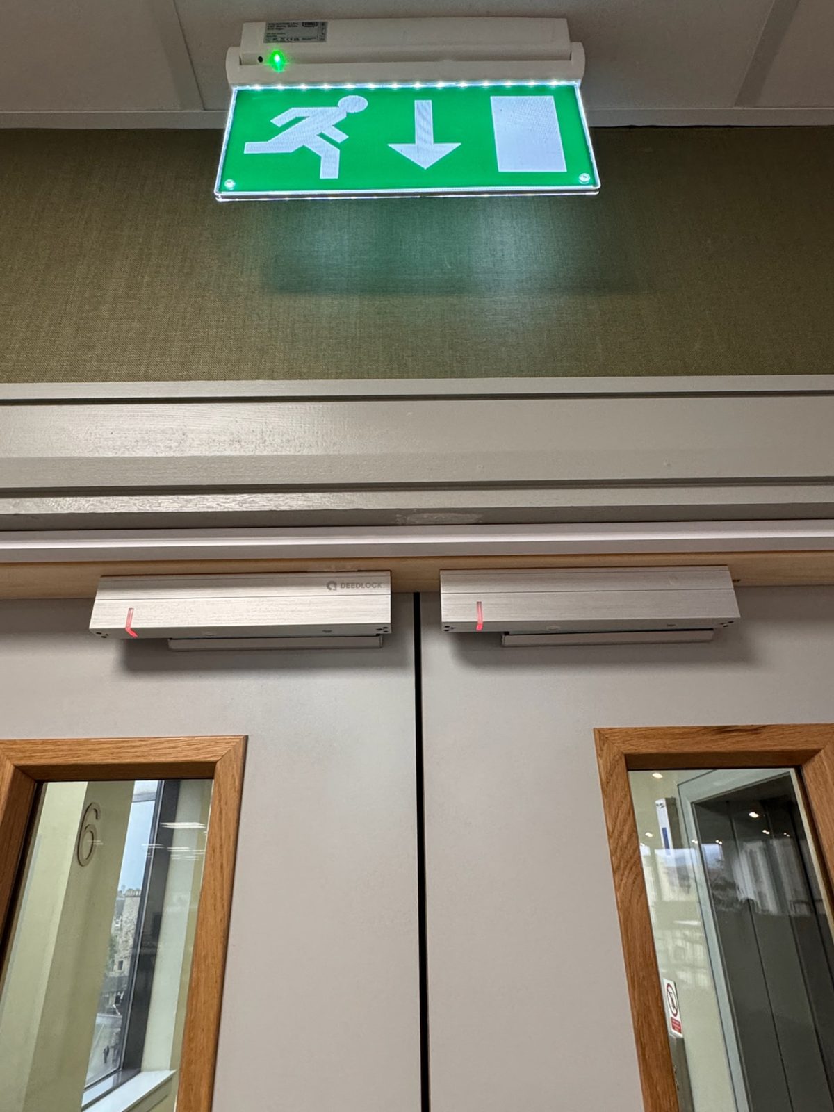 Illuminated exit sign above self-closing fire doors