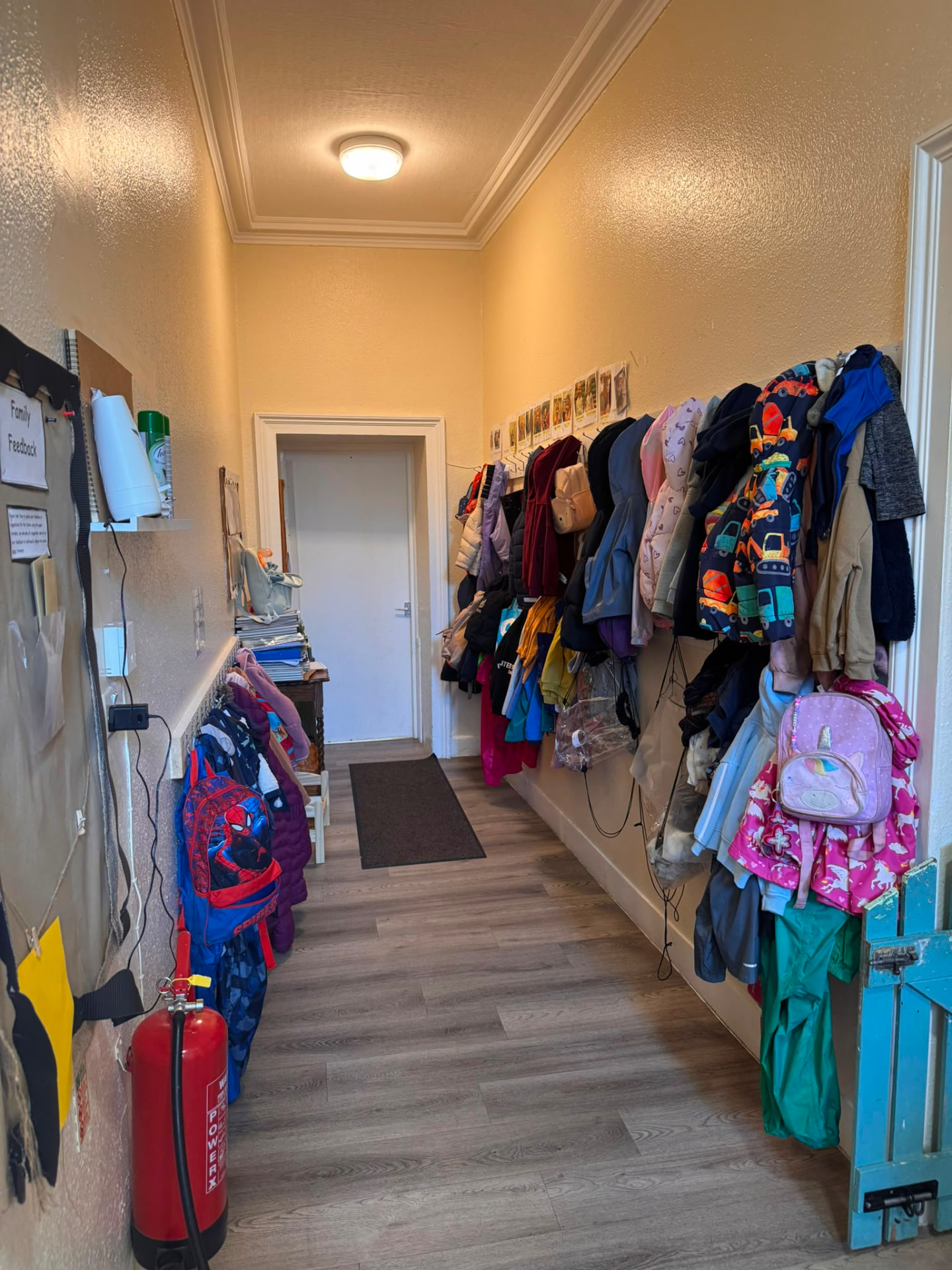 Nursery cloakroom hallway with children's coats, bags and a fire extinguisher on the escape route