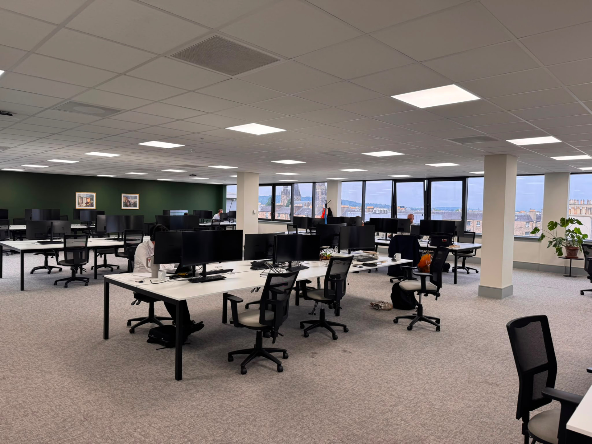 Upper-floor open-plan office with desks and escape routes between workstations