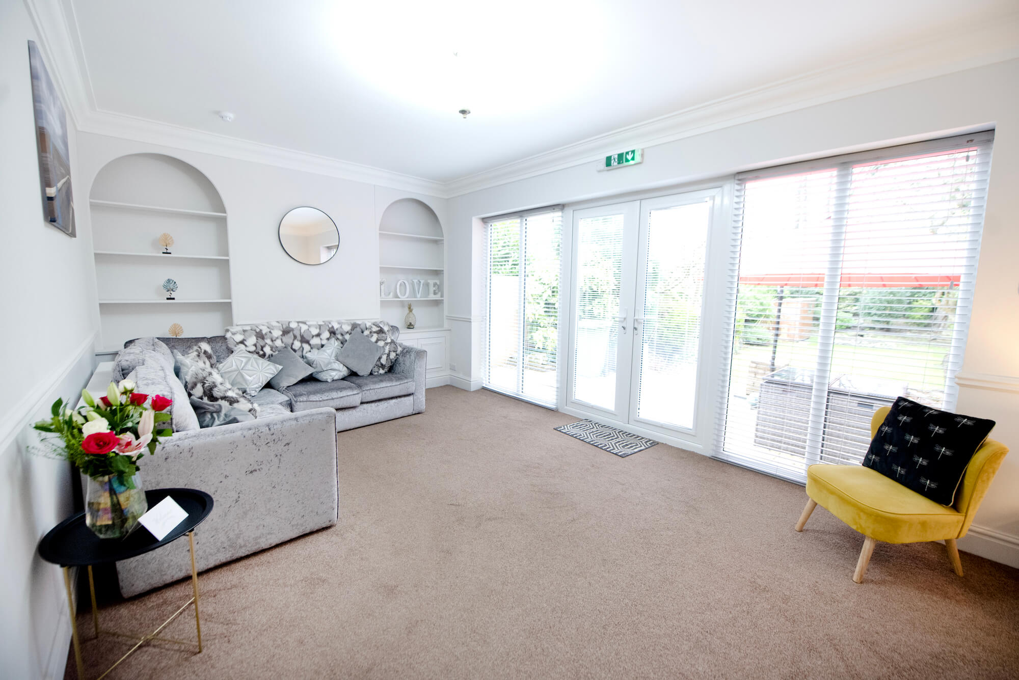 Lounge in a short-term let apartment, with an emergency exit sign above the patio doors