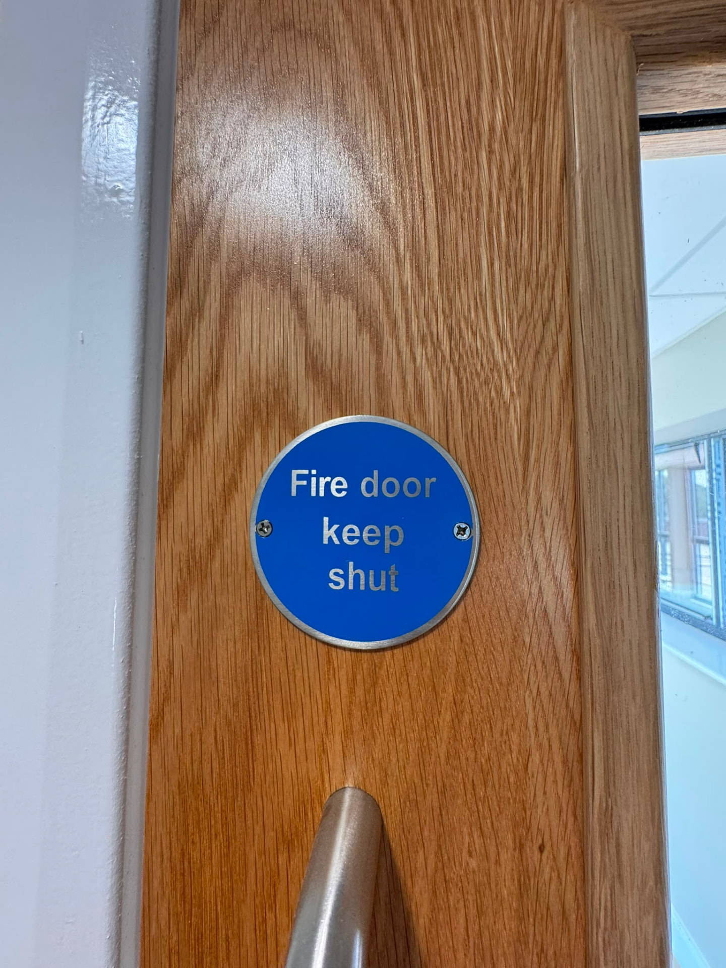 Fire door keep shut sign on a timber fire door in a small retail premises