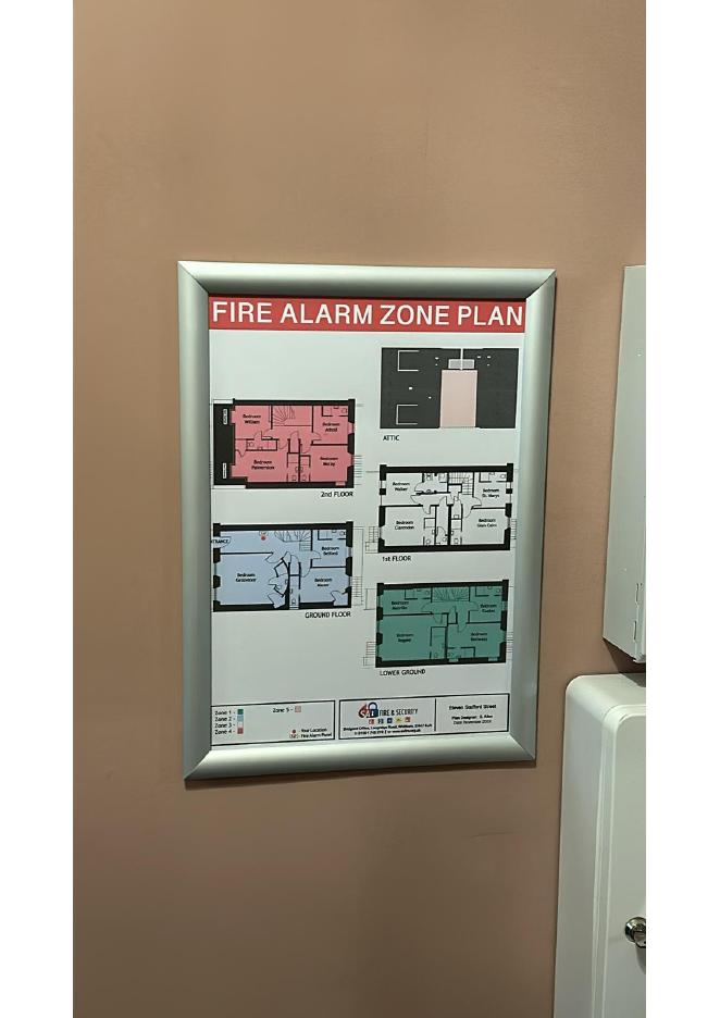Fire alarm zone plan displayed in a communal area showing colour-coded floor layouts and zones