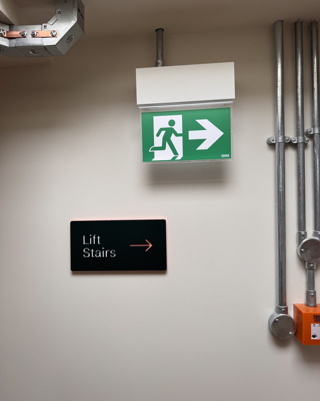Illuminated fire exit sign and lift/stairs wayfinding in an aparthotel escape route