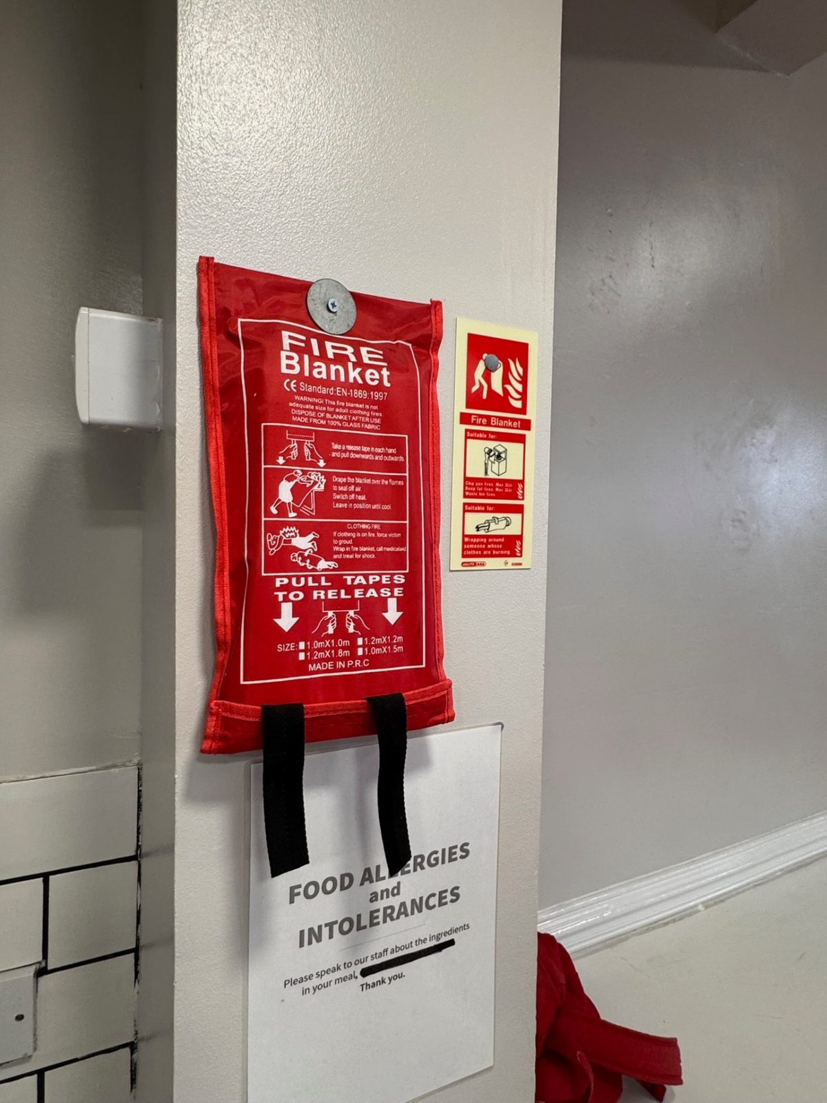 Fire blanket and fire safety equipment mounted in a commercial kitchen