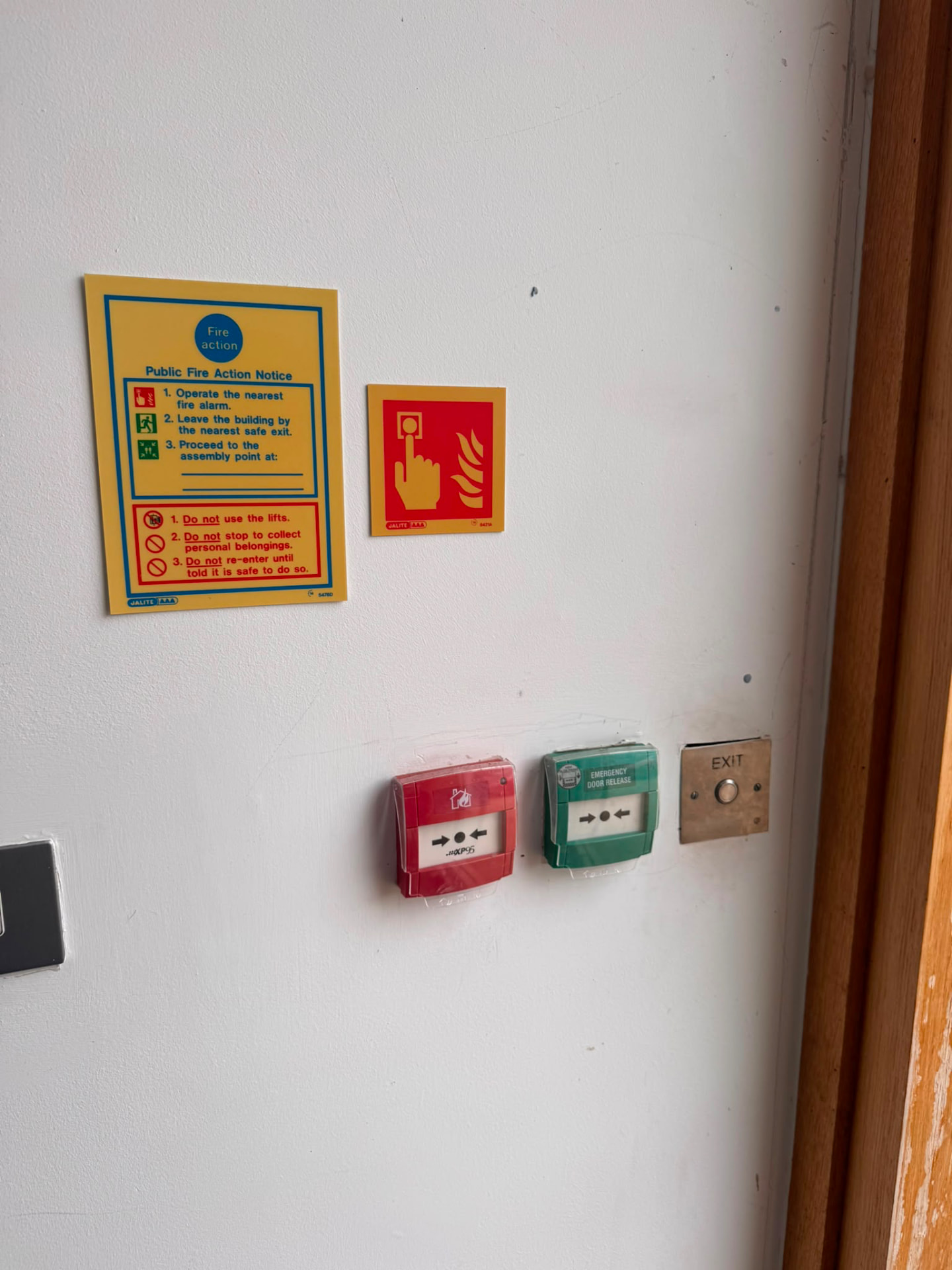 Public fire action notice, call point and emergency door release beside a final exit